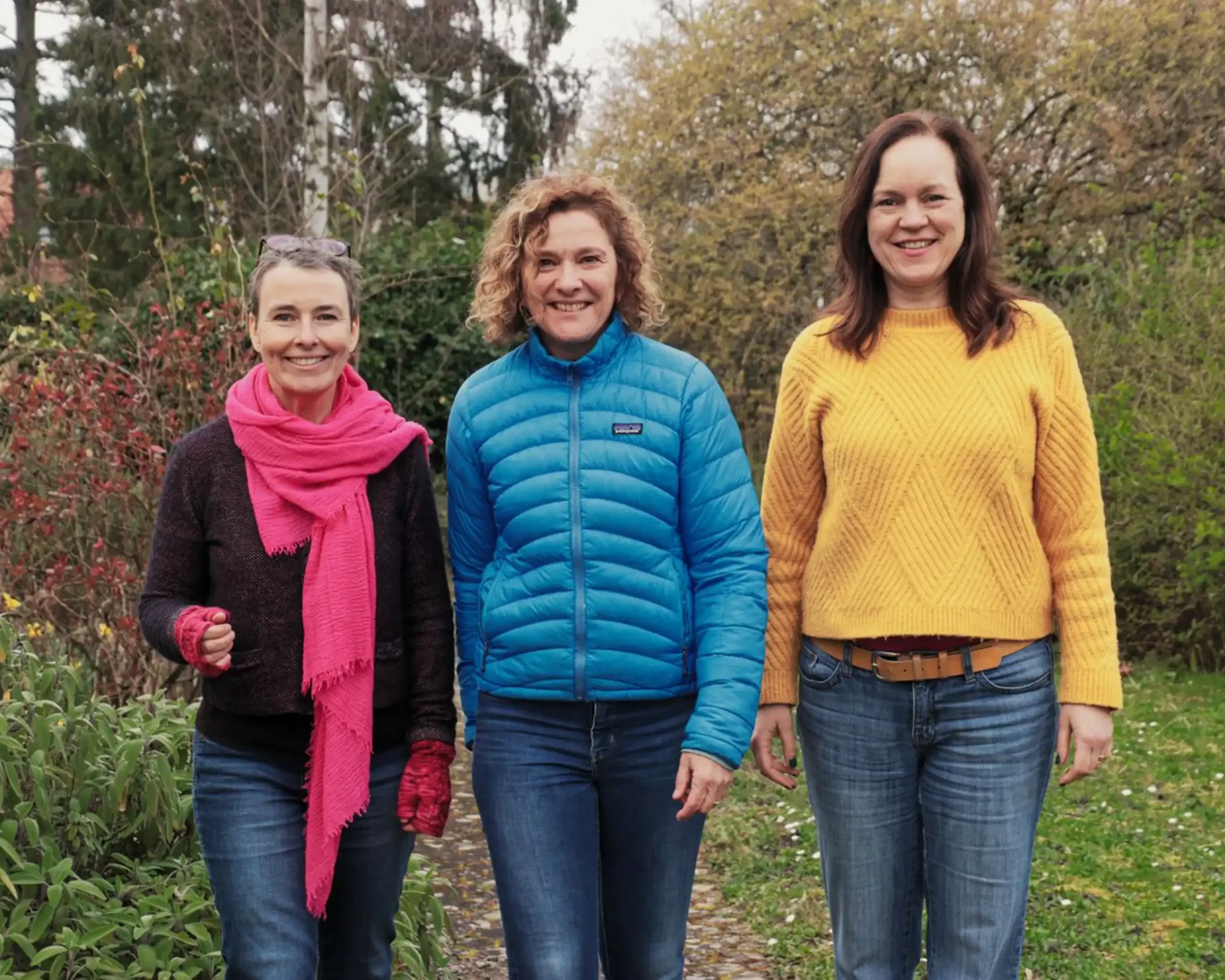 Drei freundlich lachende Frauen auf Wiese.