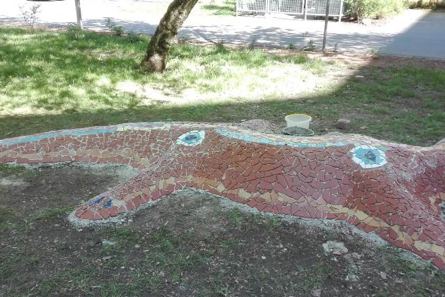 Eine ca. 5 Meter lange Betonskulptur am Eingang des PikoParks, die einen Salamander darstellt. Mit braunen, blauen, weißen Mosaiksteinen verziert.